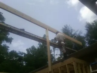 Carpenter setting a ridge beam over a new addition frame — Ice Dam Removal by Roofing Brothers in Schwertner
