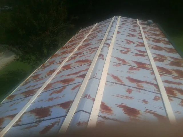 Rusted metal roof panels with new wood purlins before replacement — Storm Damage Roof Repair in Schwertner by Roofing Brothers