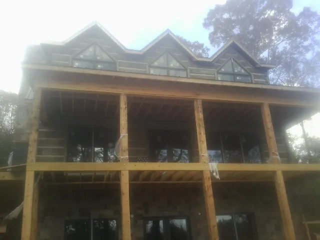 Dormers and porch framing on a large log home under construction — Roof Coating work by our crew in Schwertner