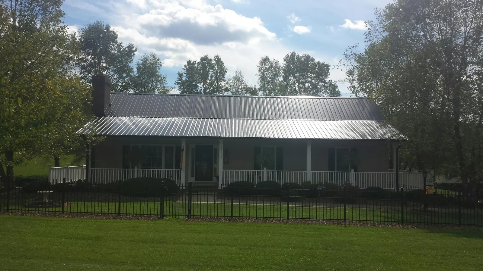 Gray metal roof on a brick ranch with a full width front porch — Gutter Guard Installation work by our crew in Schwertner
