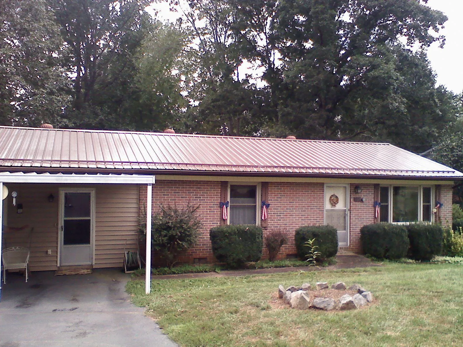 Bronze metal roof and carport on a brick ranch home — Roof Repair work by our crew in Schwertner